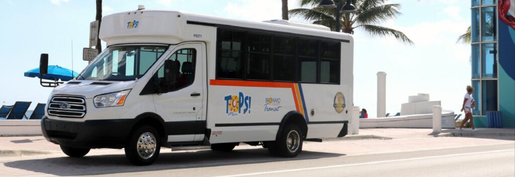 Transportation van with TOPS logo on the side, a person walking the opposite direction behind it